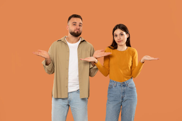 Confused Man And Woman Standing Against Orange Background During Daytime